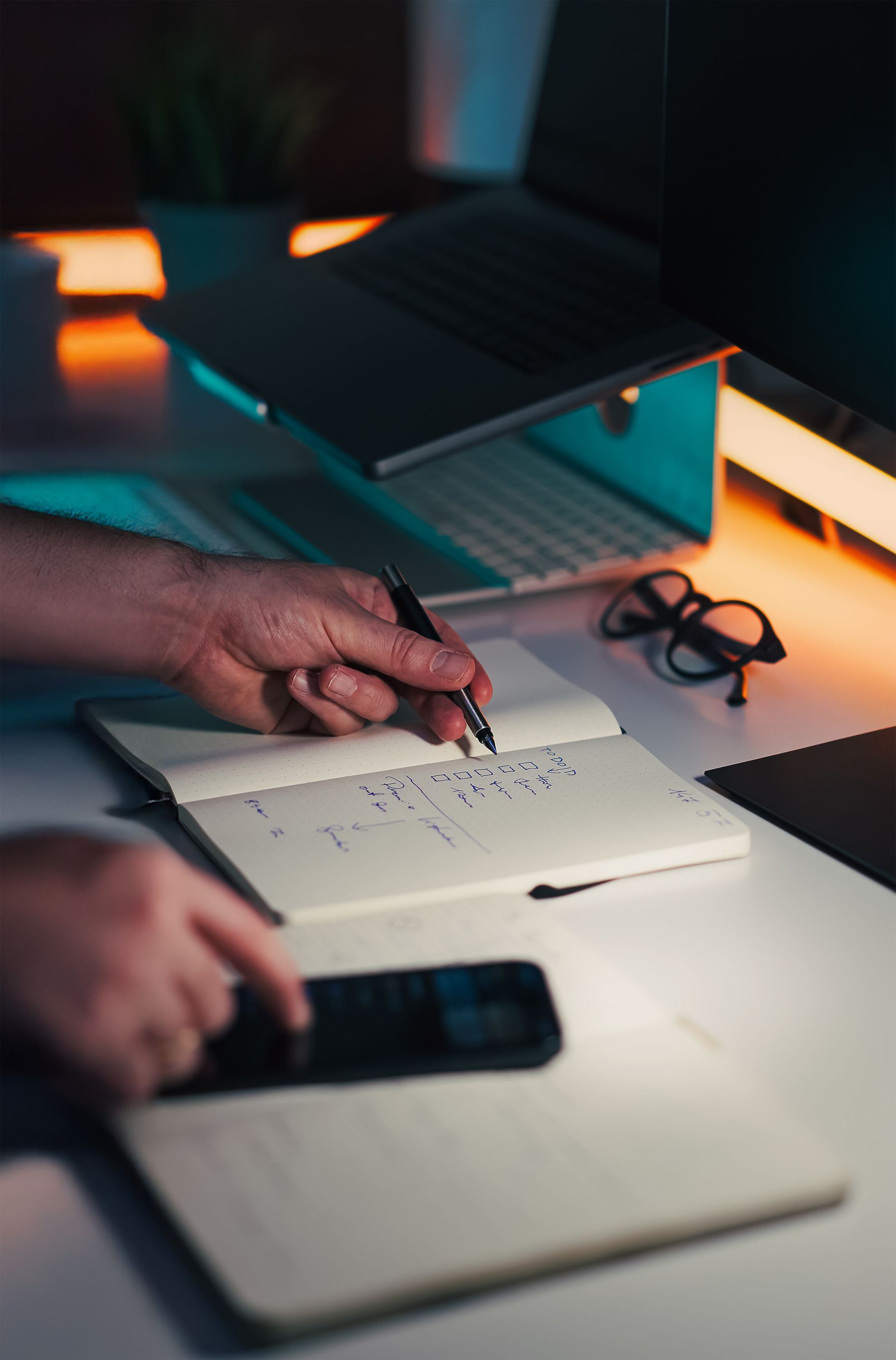 Notebook and laptop on a modern office desk with smartphone nearby