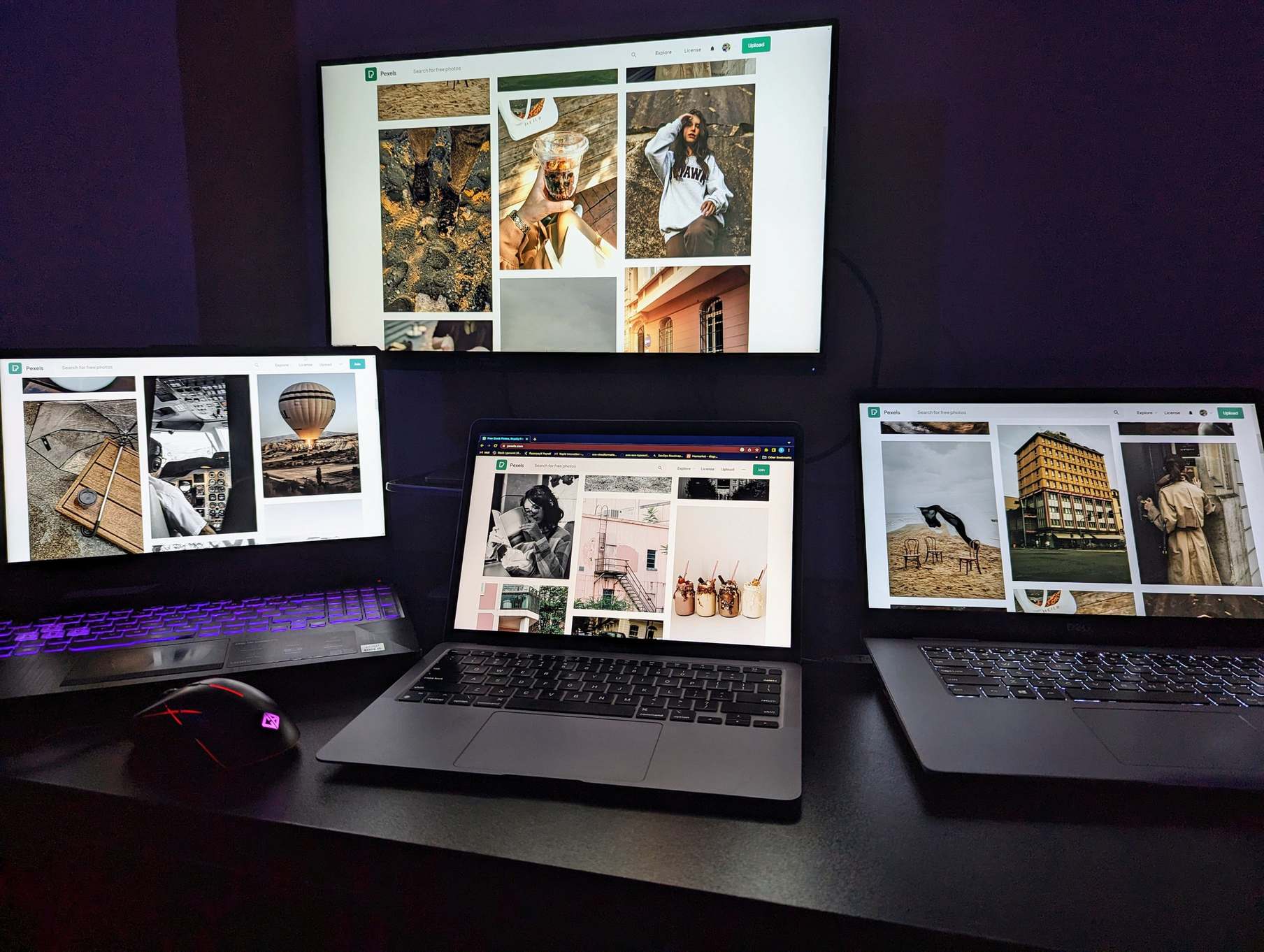 Laptops and a monitor on a desk in dim light